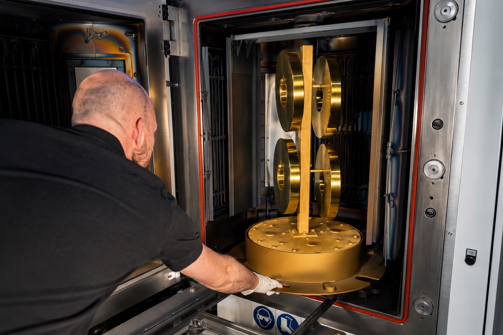 Goldglänzende PVD-beschichtete Bauteile beim Bestücken der Beschichtungsanlage
